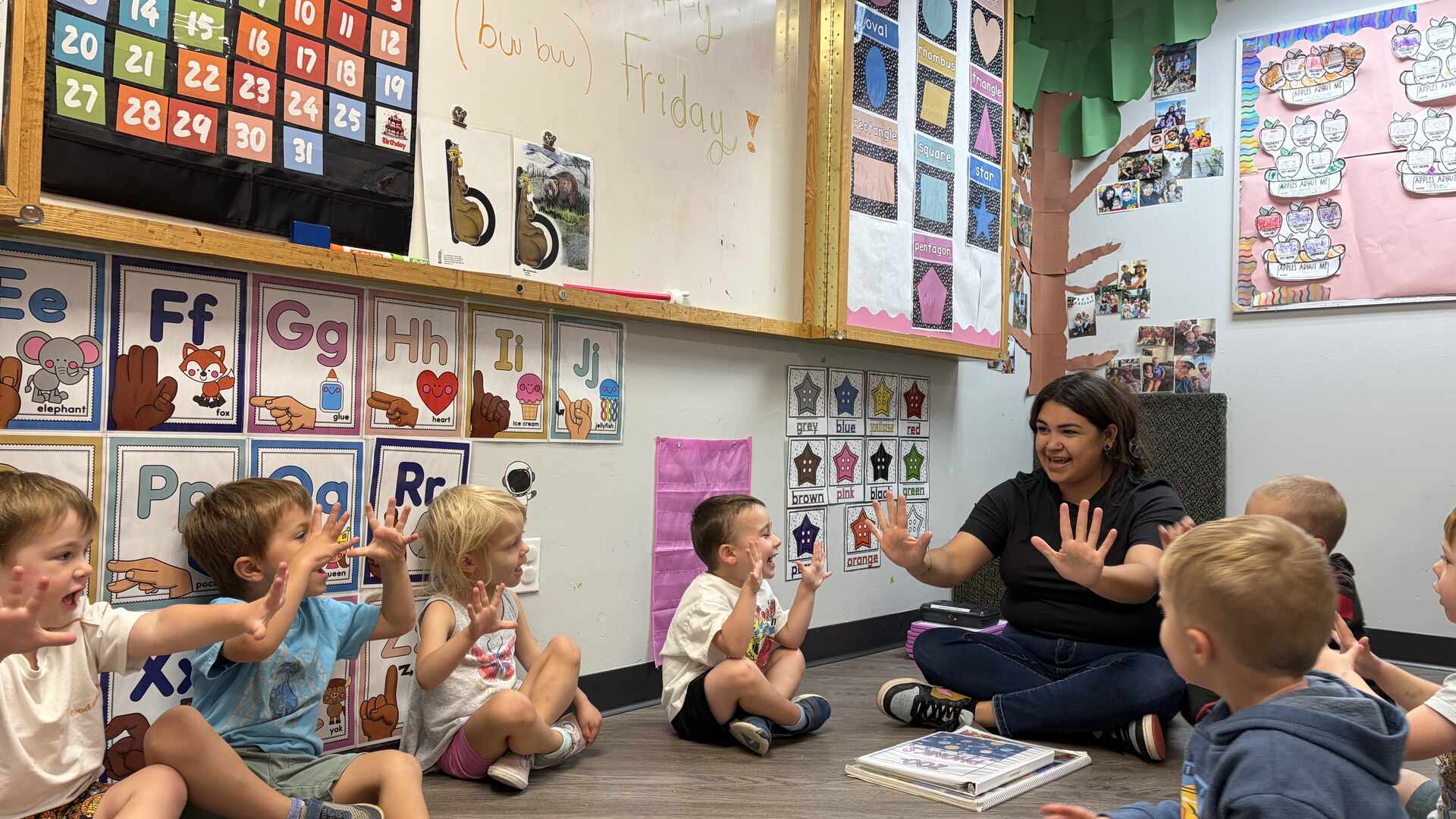 Teacher leading preschoolers in circle time on the classroom floor